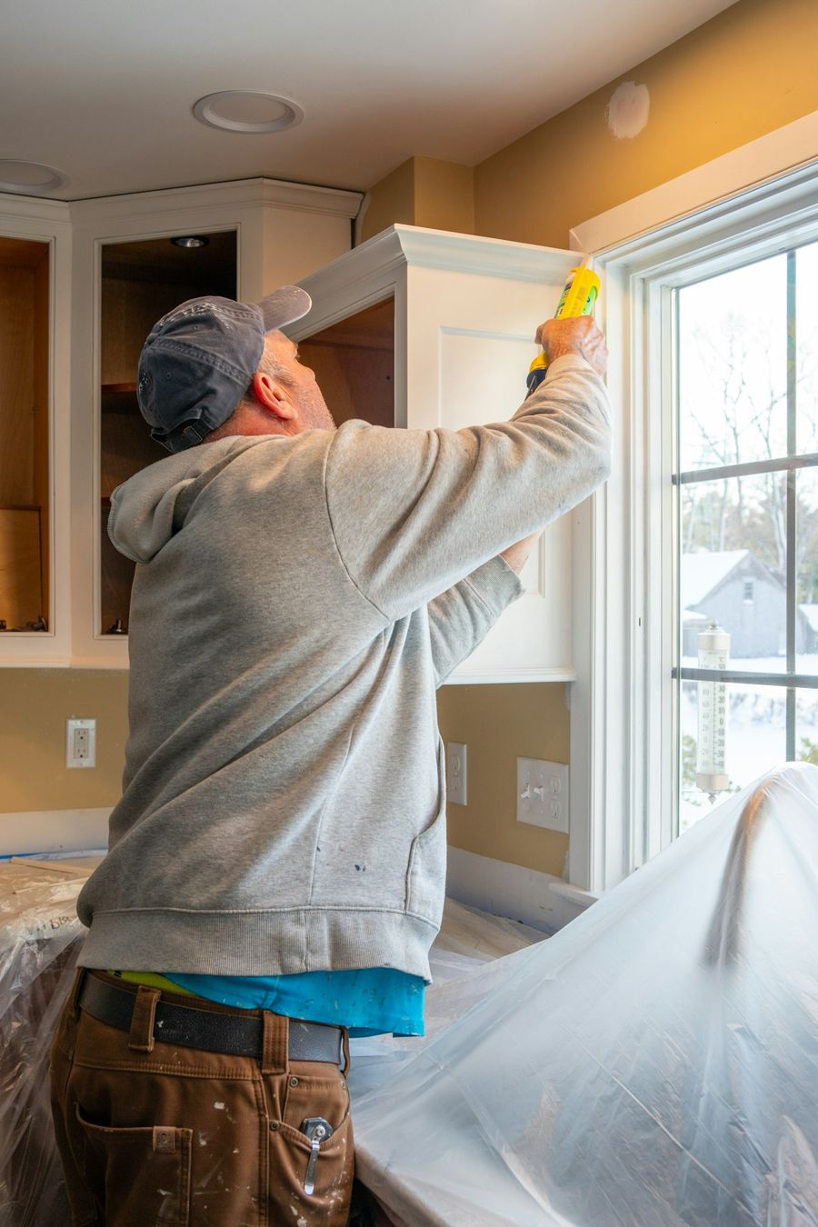 Painter carefully prepping trim and window casing before painting