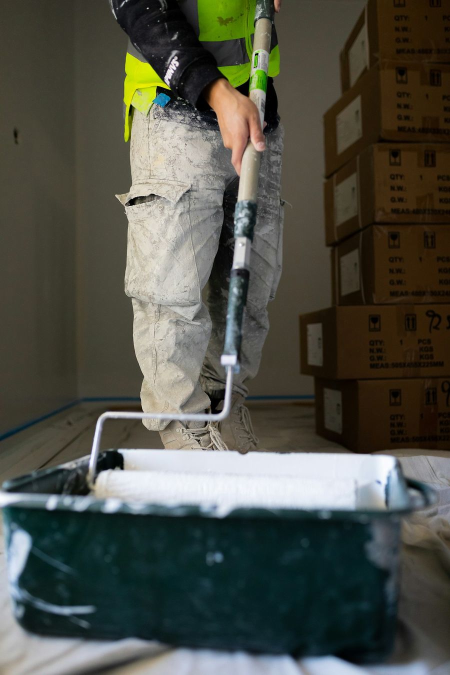 Painter rolling fresh white paint onto an interior wall